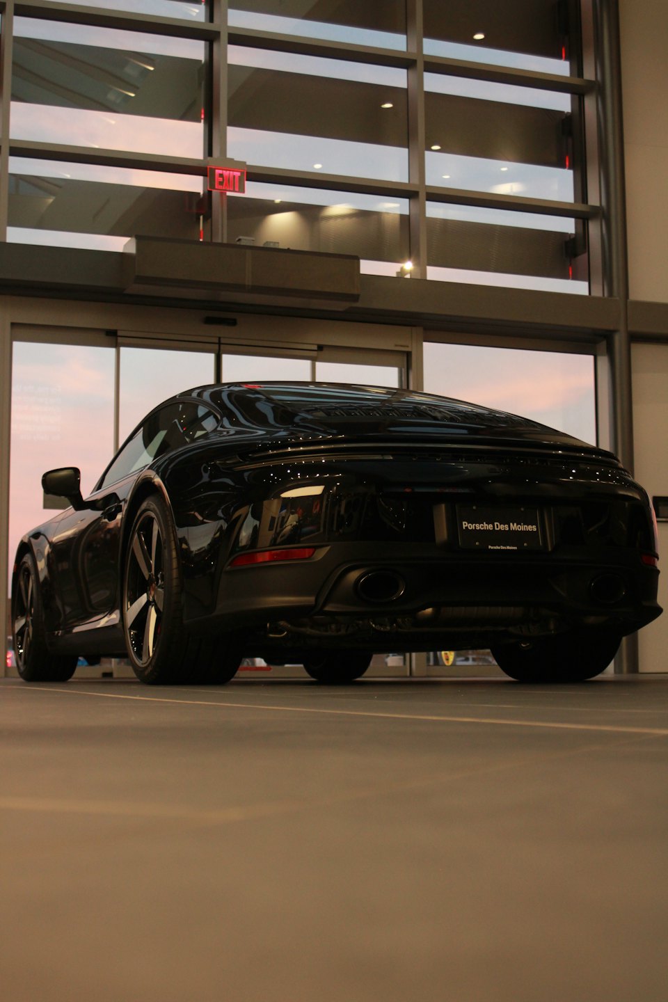Black sports car parked inside a modern glass showroom.
