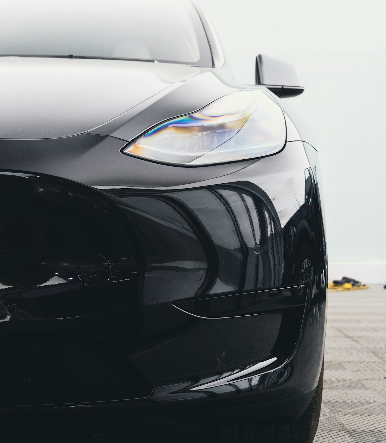 Sleek black modern car with visible headlight and aerodynamic design.
