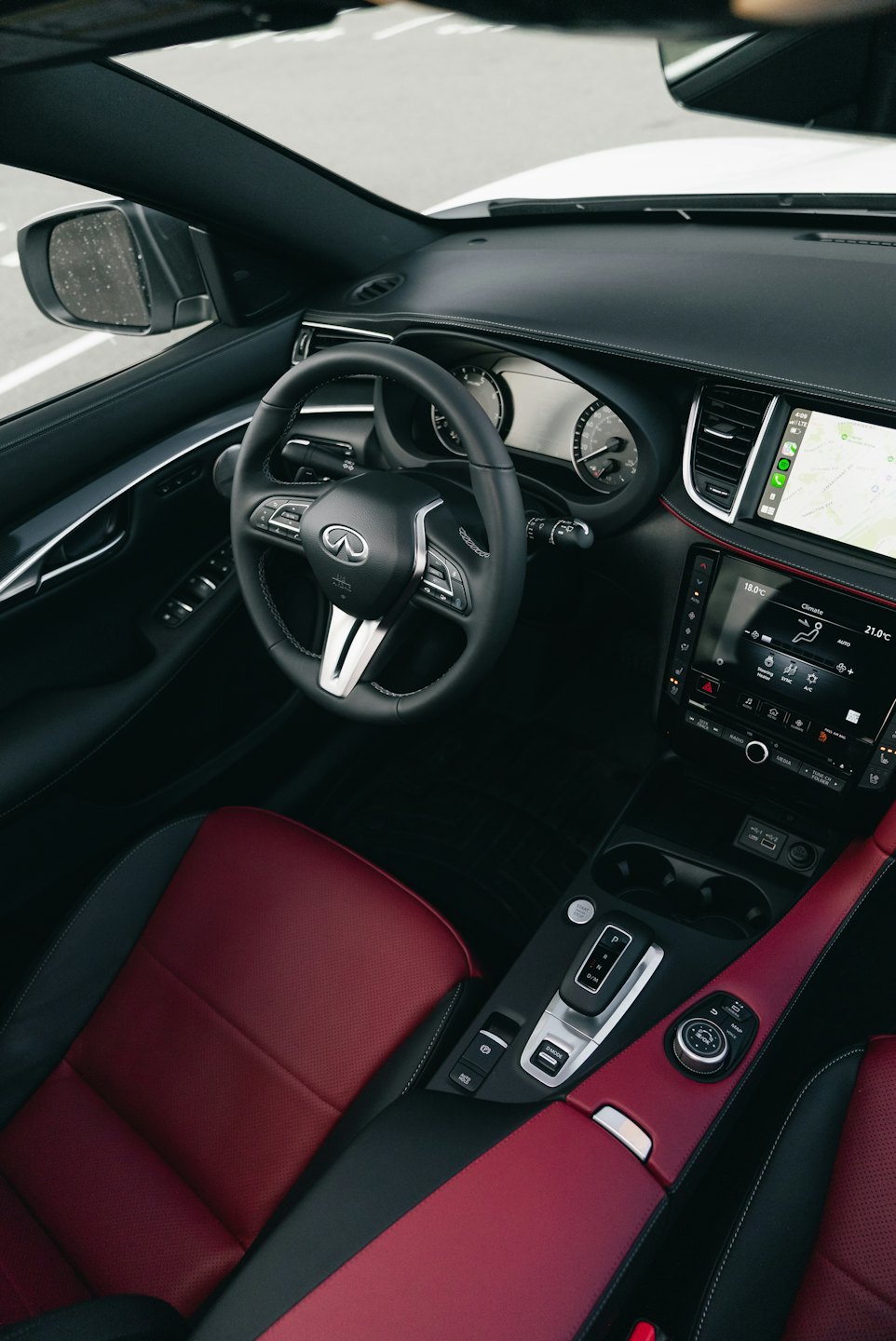 Luxury vehicle dashboard with red leather seats and navigation display.